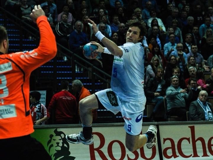 Handballspieler beim Sprungwurf in einer vollen Halle